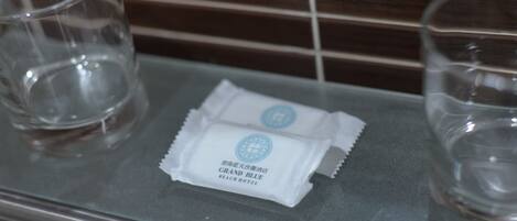 A bathroom counter with two empty glasses and a packet labeled "GRAND BLUE BEACH HOTEL".