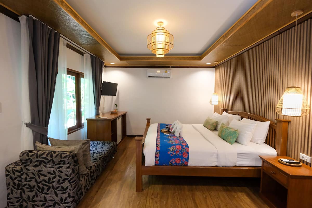 Una habitación de hotel con una cama de madera, un escritorio, una silla y una mesita de noche con lámpara.