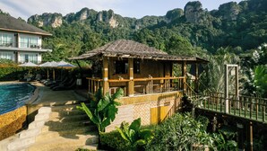 A resort with a pool, a wooden structure with a thatched roof, and a mountain backdrop. - Railay Phutawan Resort (Krabi)
