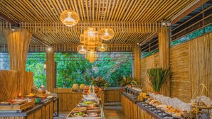 A buffet setup with various food items and a central serving area, surrounded by wooden walls and a bamboo ceiling. - Railay Phutawan Resort (Krabi)