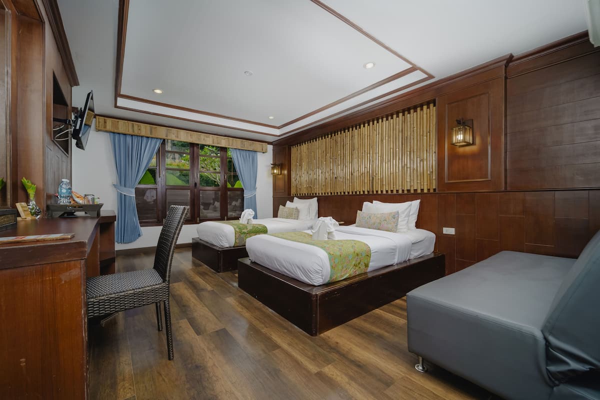 A hotel room with two beds, a desk, and a sofa.