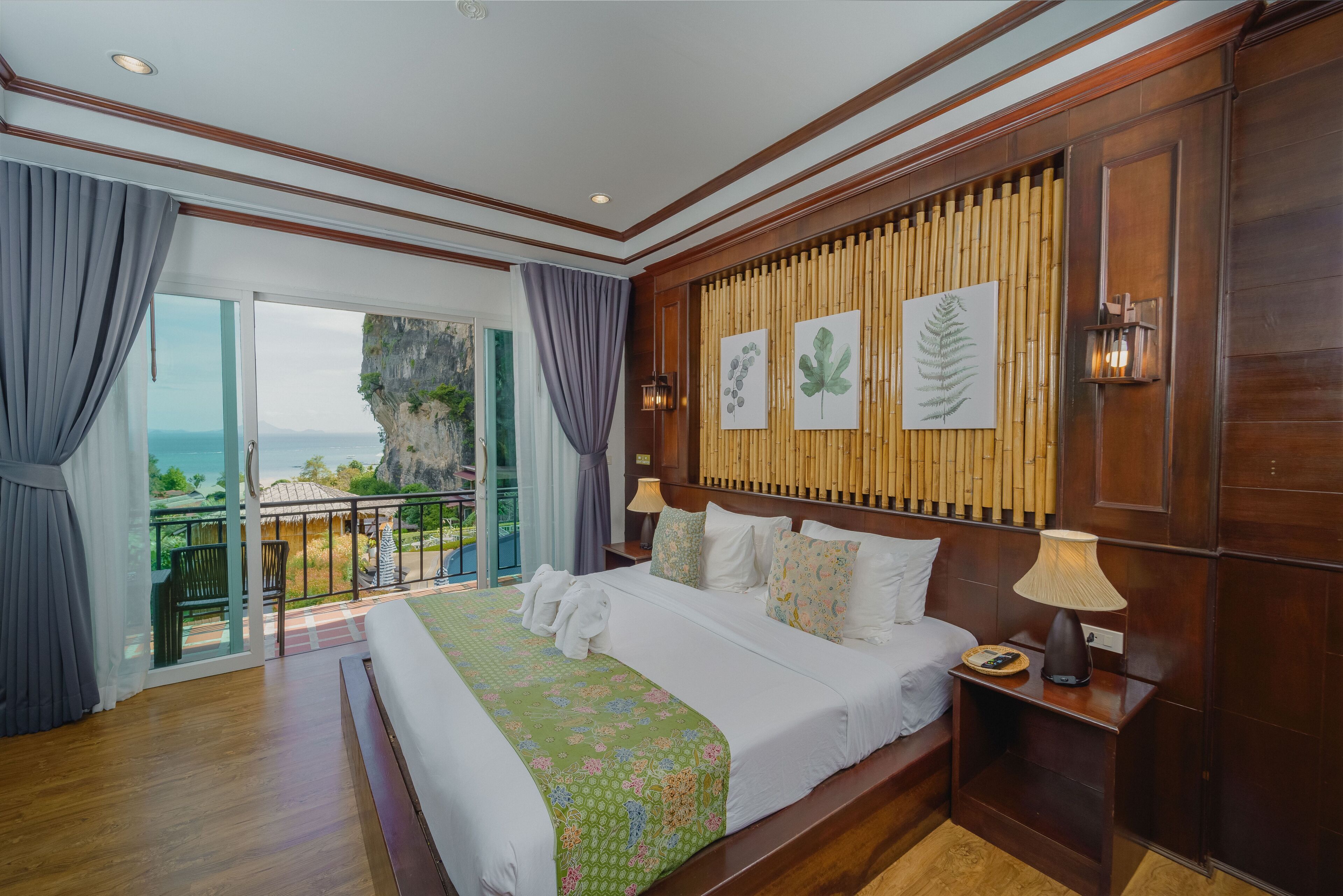 A spacious bedroom with a large bed, a balcony with a view, and wooden paneling on the walls.