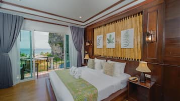A spacious bedroom with a large bed, a balcony with a view, and wooden paneling on the walls.