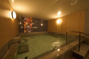 A hot tub with a wooden wall and a mural, surrounded by stone steps and railings. - Hotel Hokke Club Fukuoka (Fukuoka)