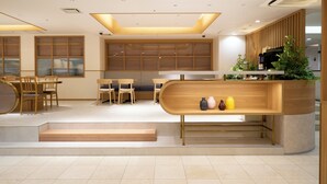 A modern interior with a wooden reception desk, seating area, and a staircase leading to an upper level. - Hotel Hokke Club Fukuoka (Fukuoka)