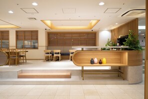 A modern interior with a wooden reception desk, seating area, and a staircase leading to an upper level. - Hotel Hokke Club Fukuoka (Fukuoka)