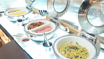 A buffet setup with various dishes including pasta, sausages, and a bowl of soup.