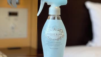 Un flacone spray con l'etichetta ‘FABRIC & AIR’ su un piano di legno.