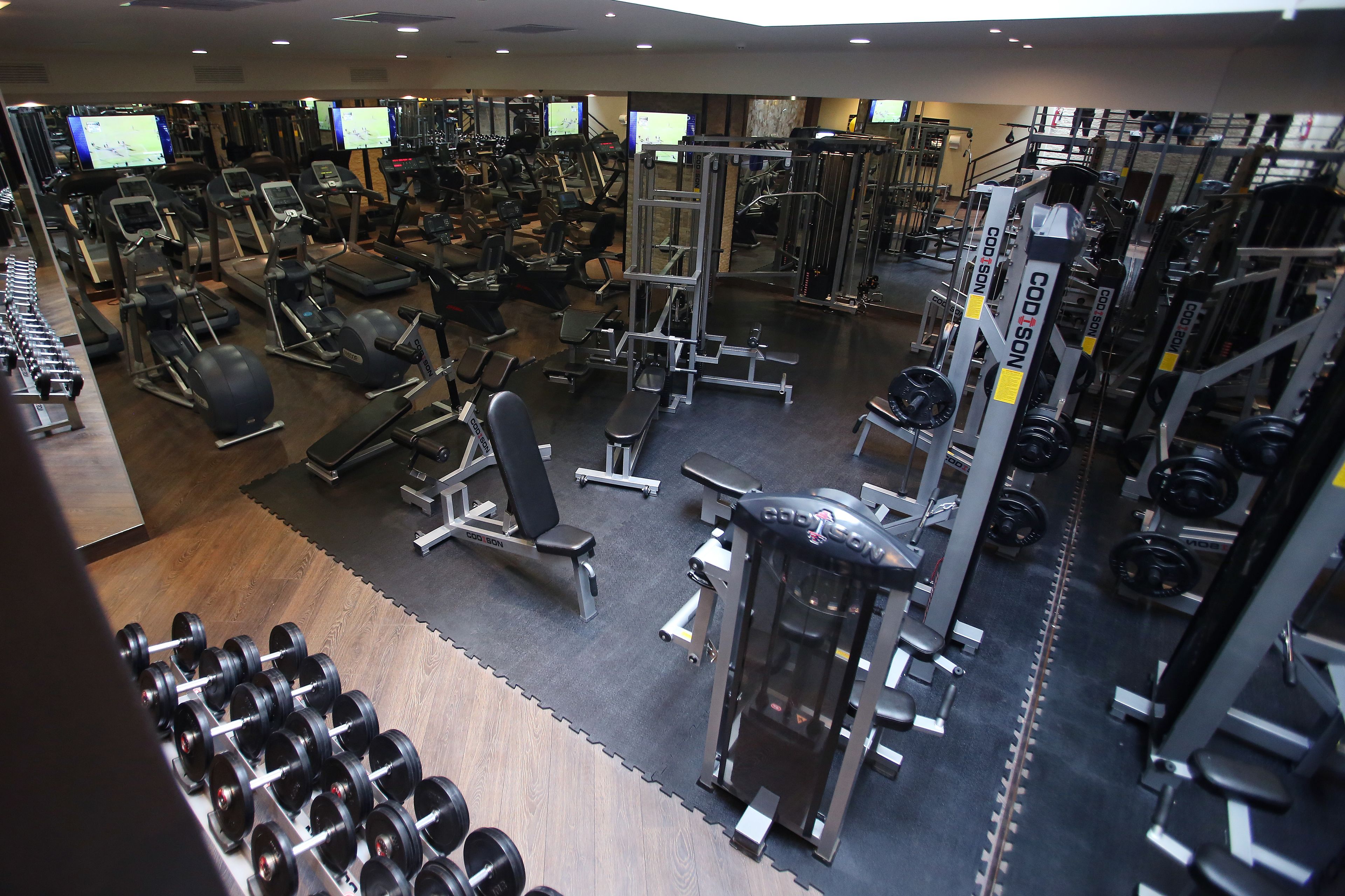 A gym with various exercise equipment, including treadmills, weight machines, and free weights.
