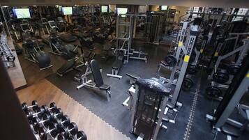 A gym with various exercise equipment, including treadmills, weight machines, and free weights.