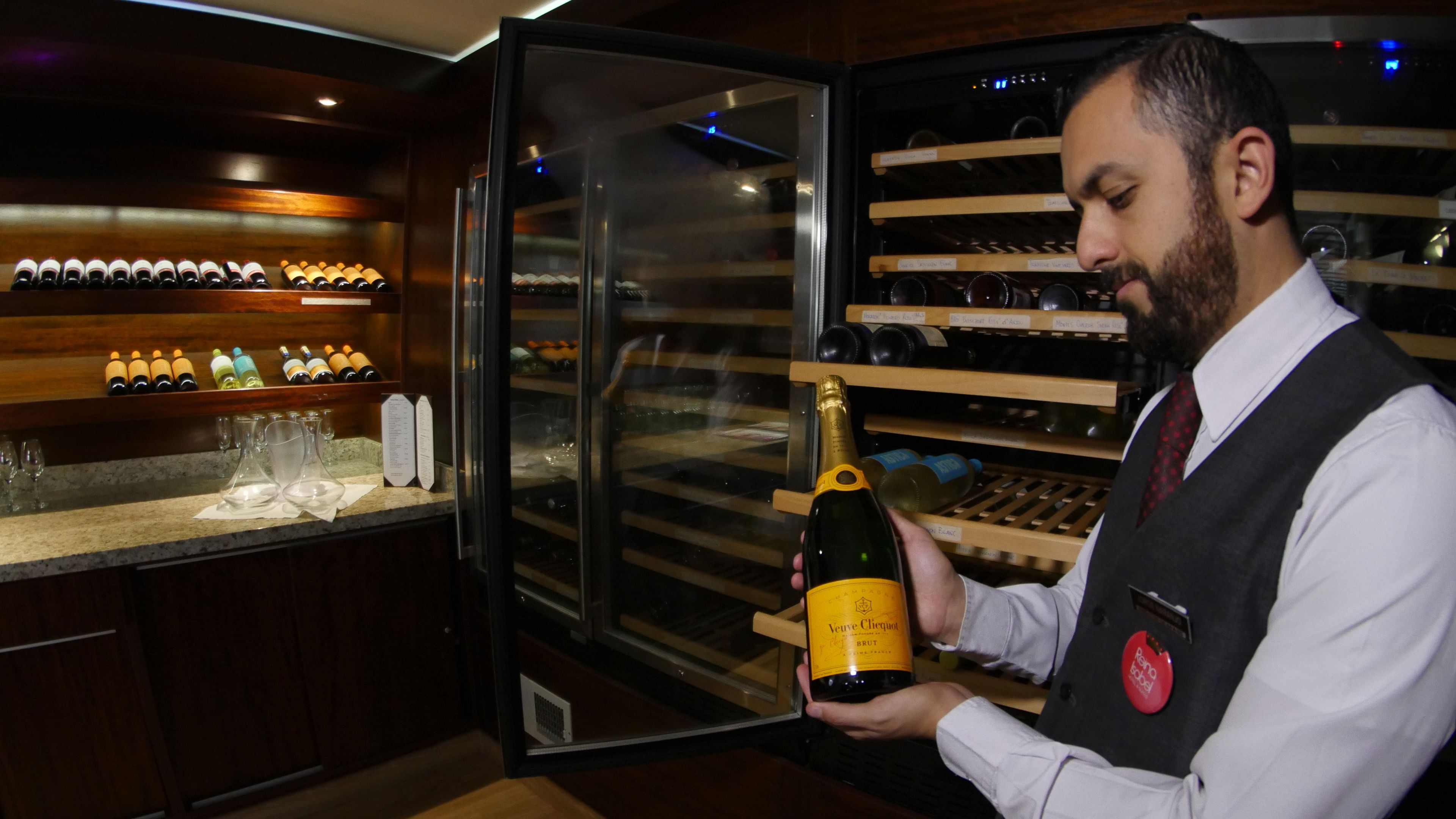 A bar area with a wine rack, glasses, and a bottle of Veuve Clicquot champagne.