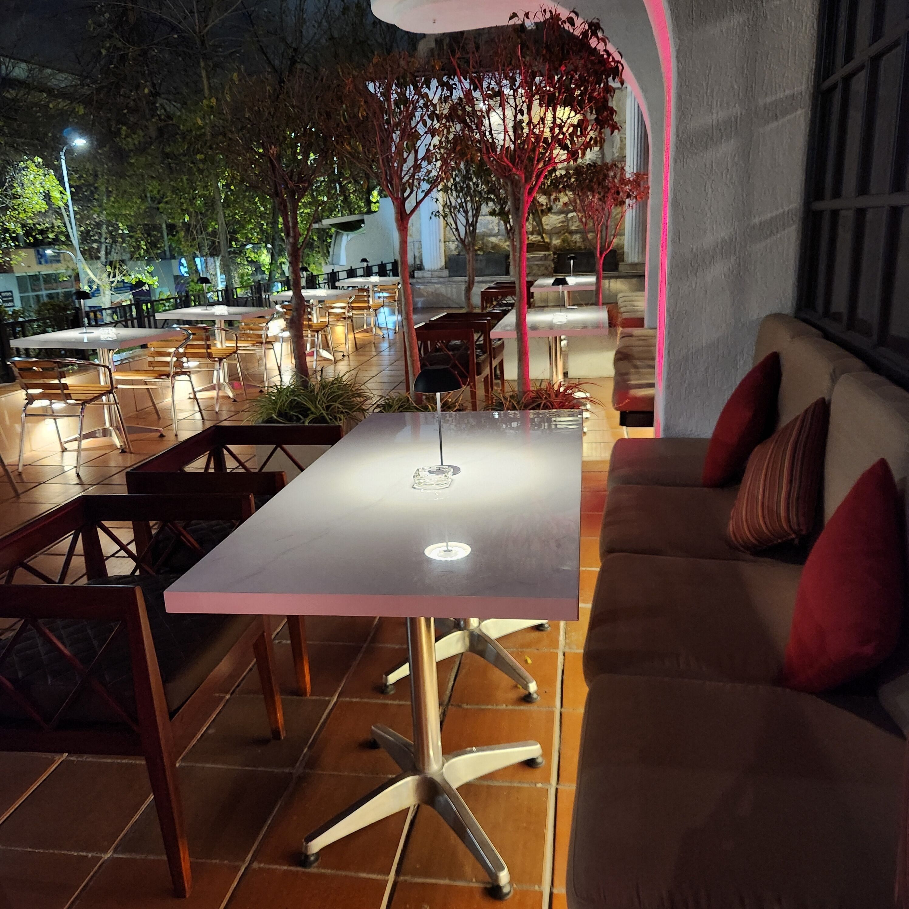 An outdoor seating area with tables and chairs, a sofa, and a decorative tree.