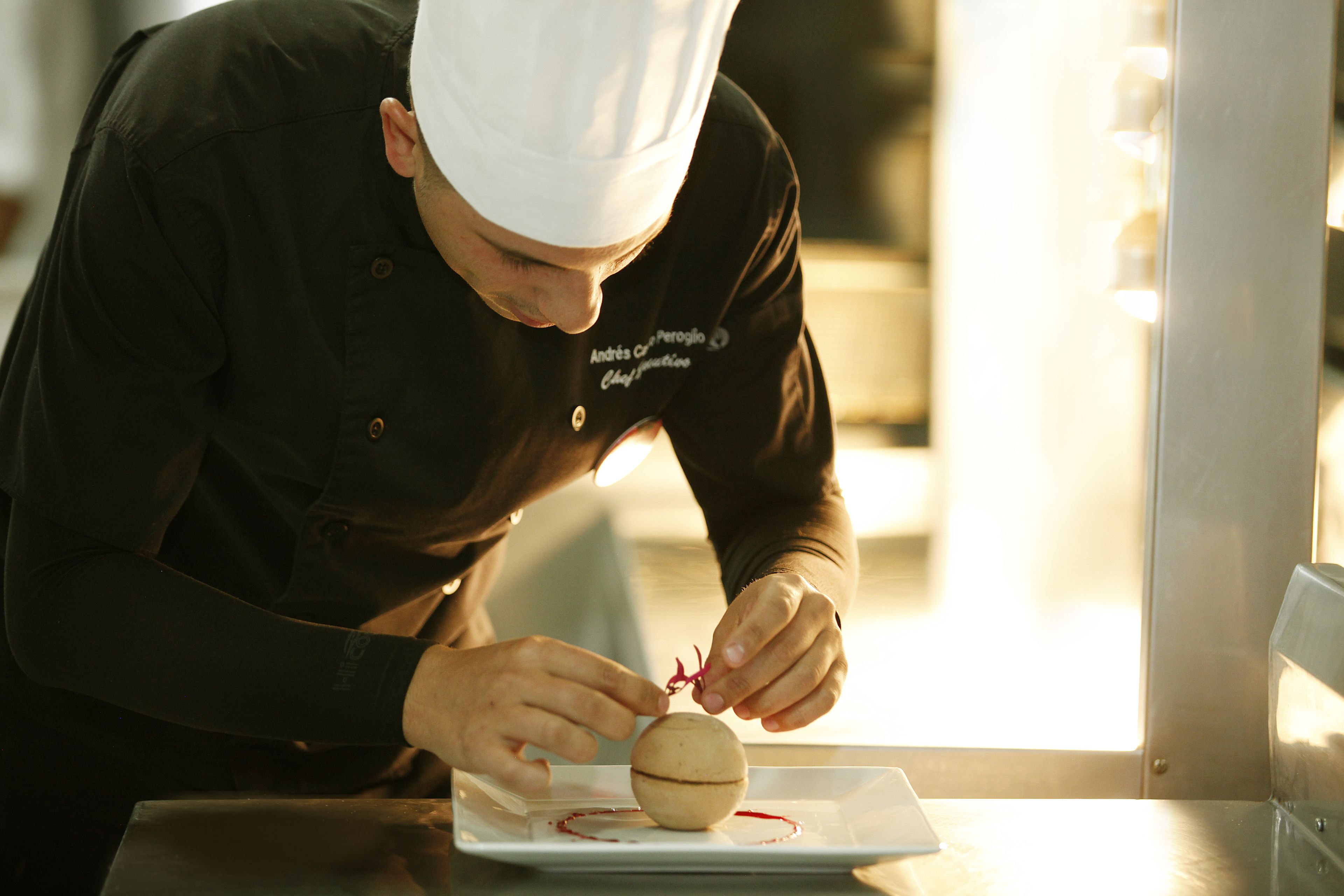 Un chef preparando un plato, destacando la presentación de la comida.