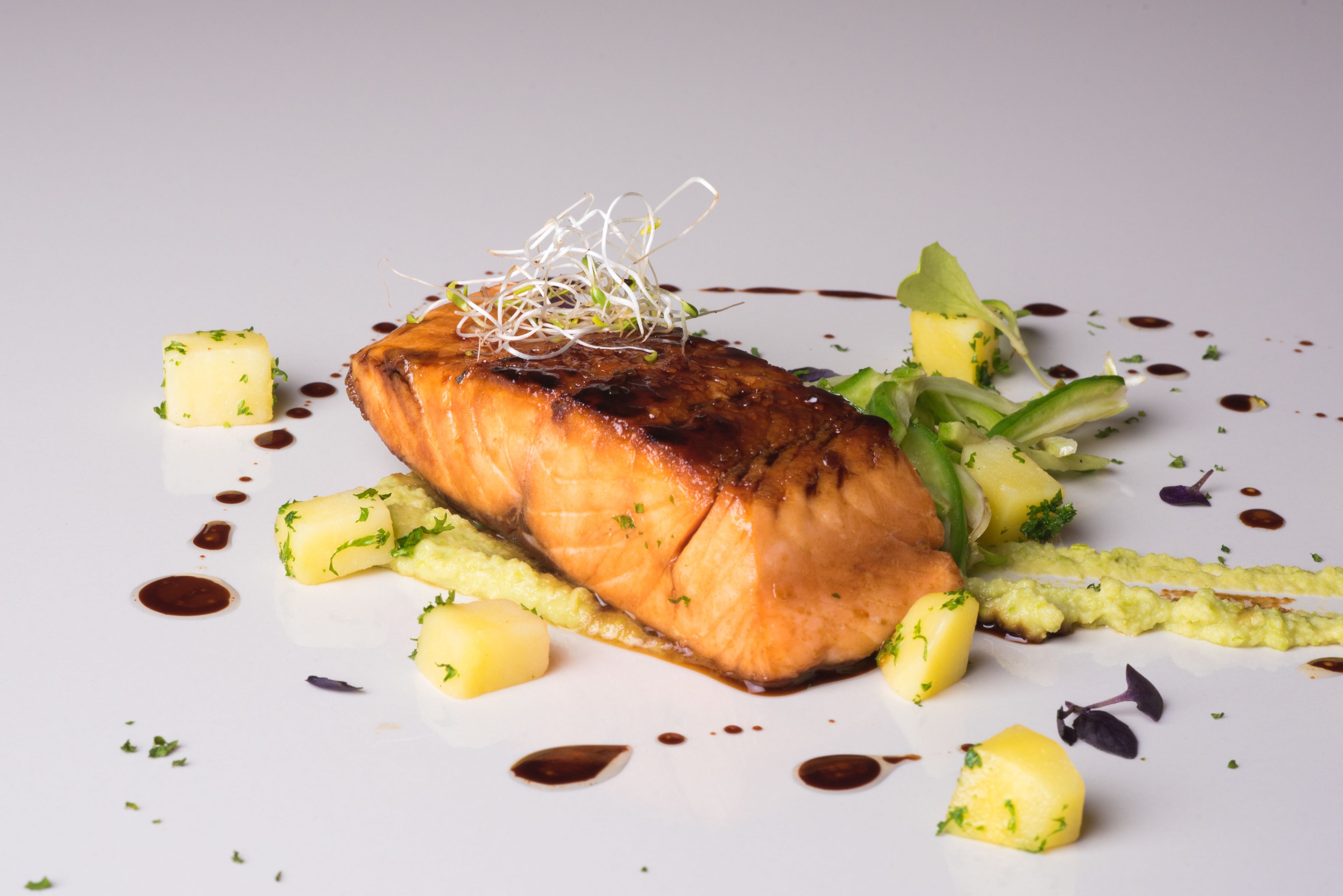 Un plato con salmón, patatas y verduras verdes.