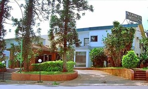 A hotel with a modern facade, a gated entrance, and a signboard. - Alexander Hotel (Iguazu)