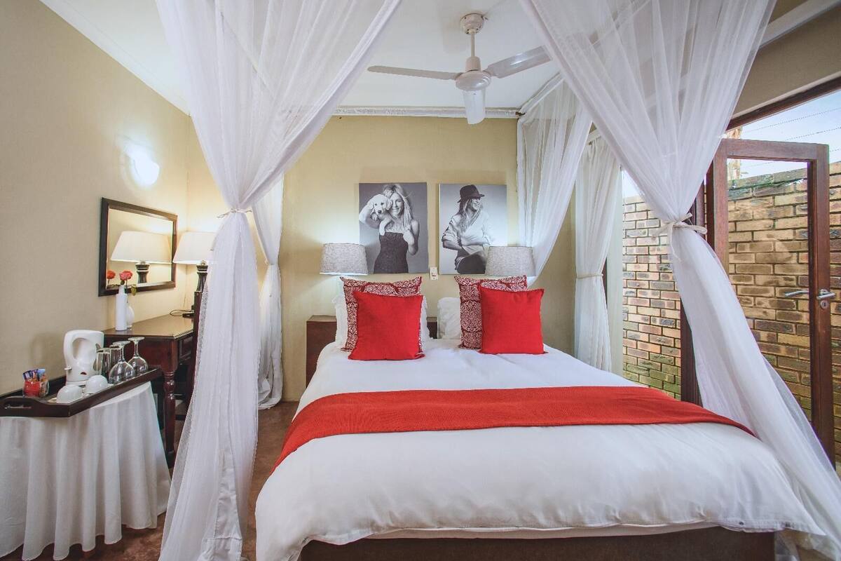 A hotel room with a bed, a bedside table, a lamp, and a window with curtains.