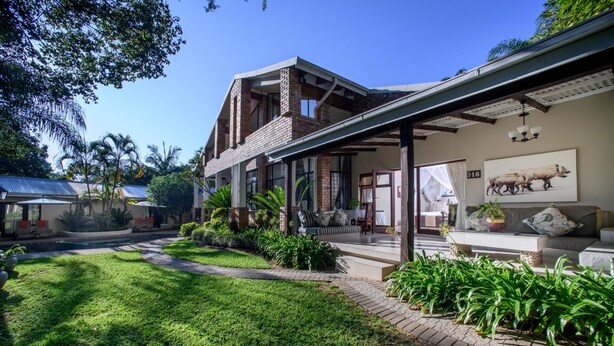 Ein modernes Haus mit geräumiger Terrasse, überdachter Sitzgelegenheit im Freien und einem gepflegten Garten.