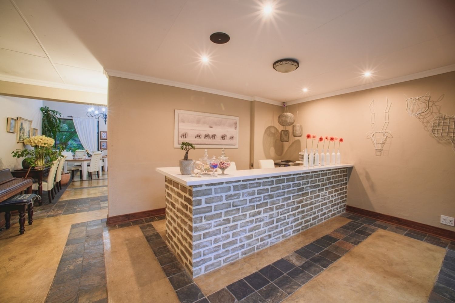 A reception area with a brick counter, a dining area with a piano, and a wall with abstract art.