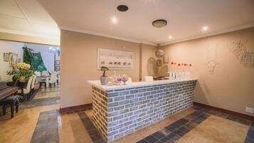A reception area with a brick counter, a dining area with a piano, and a wall with abstract art.
