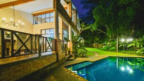 Ein modernes Haus mit Swimmingpool, überdachter Terrasse und gepflegtem Garten.