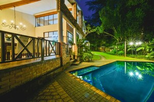 Una piscina al aire libre, sillones reclinables de piscina