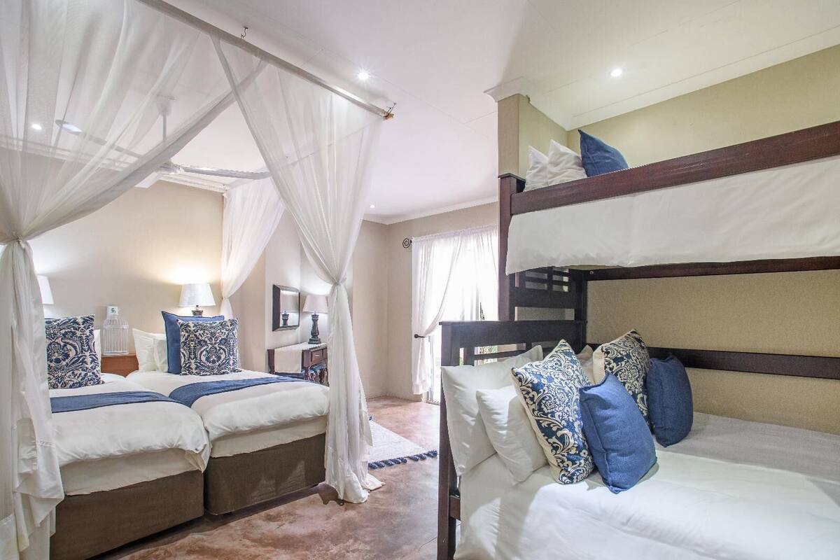 A hotel room with two beds, one with a canopy and the other with bunk beds.