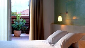 Habitación de hotel con una cama, una planta en maceta, una cortina y una l ámpara de pared.