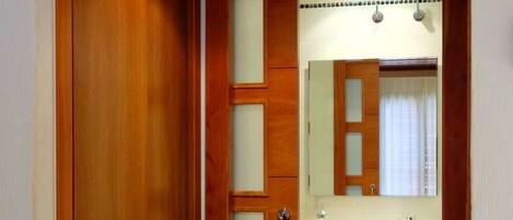 A wooden door leading to a bathroom with a glass shower enclosure and a sink.