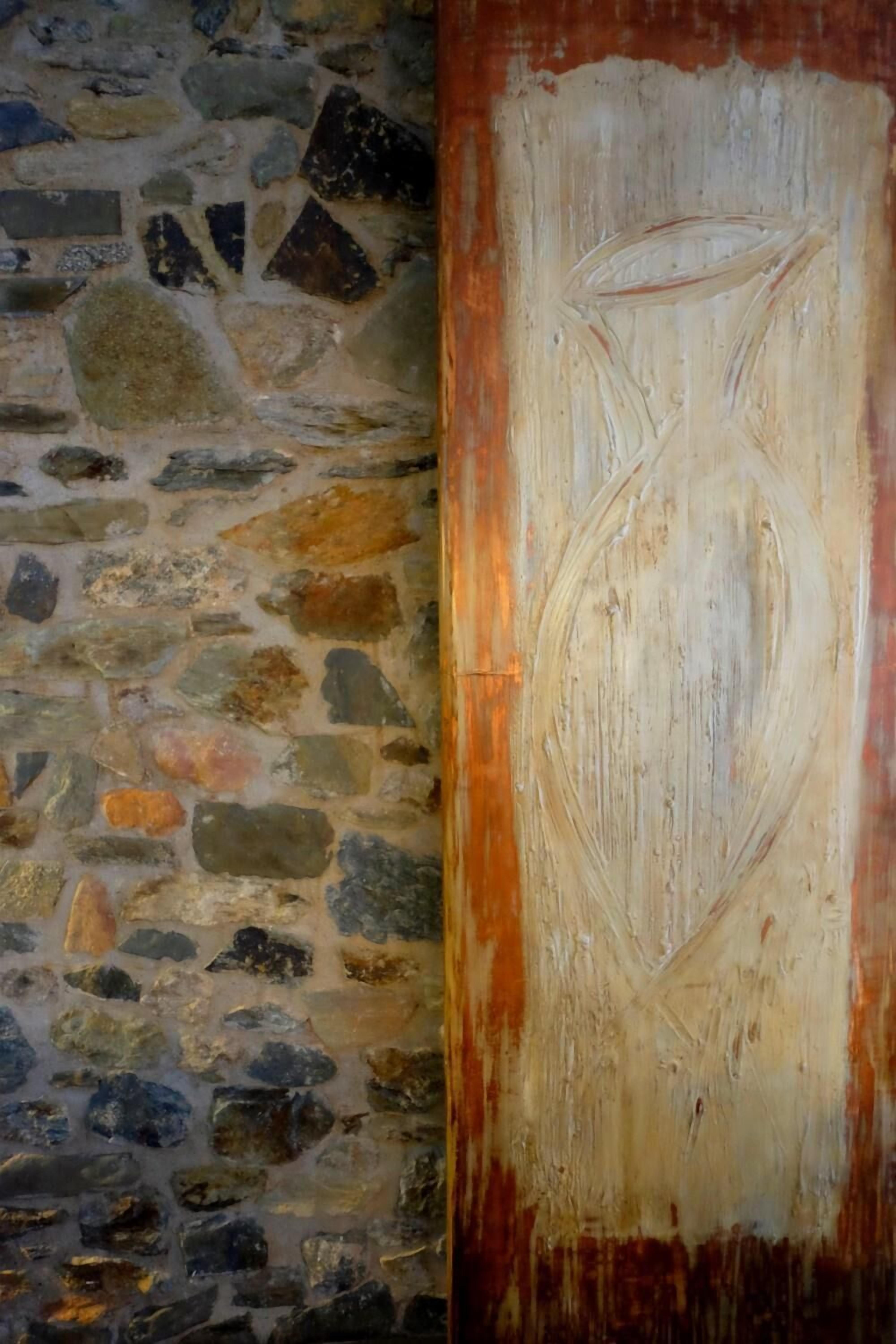 Eine steinerne Mauer mit rauer Struktur und ein Holzpaneel mit geschnitztem Dekor.