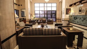 A spacious living area with a large window, a chandelier, and a marble accent wall. - Gardenia Hotel (Amman)
