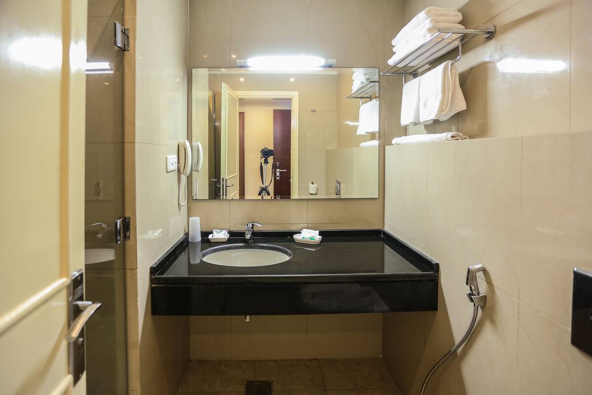 A bathroom with a black sink, a mirror, a towel rack, and a shower.