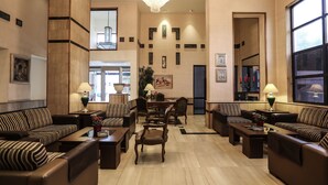 A spacious lobby with striped sofas, a dining area, and a chandelier. - Gardenia Hotel (Amman)