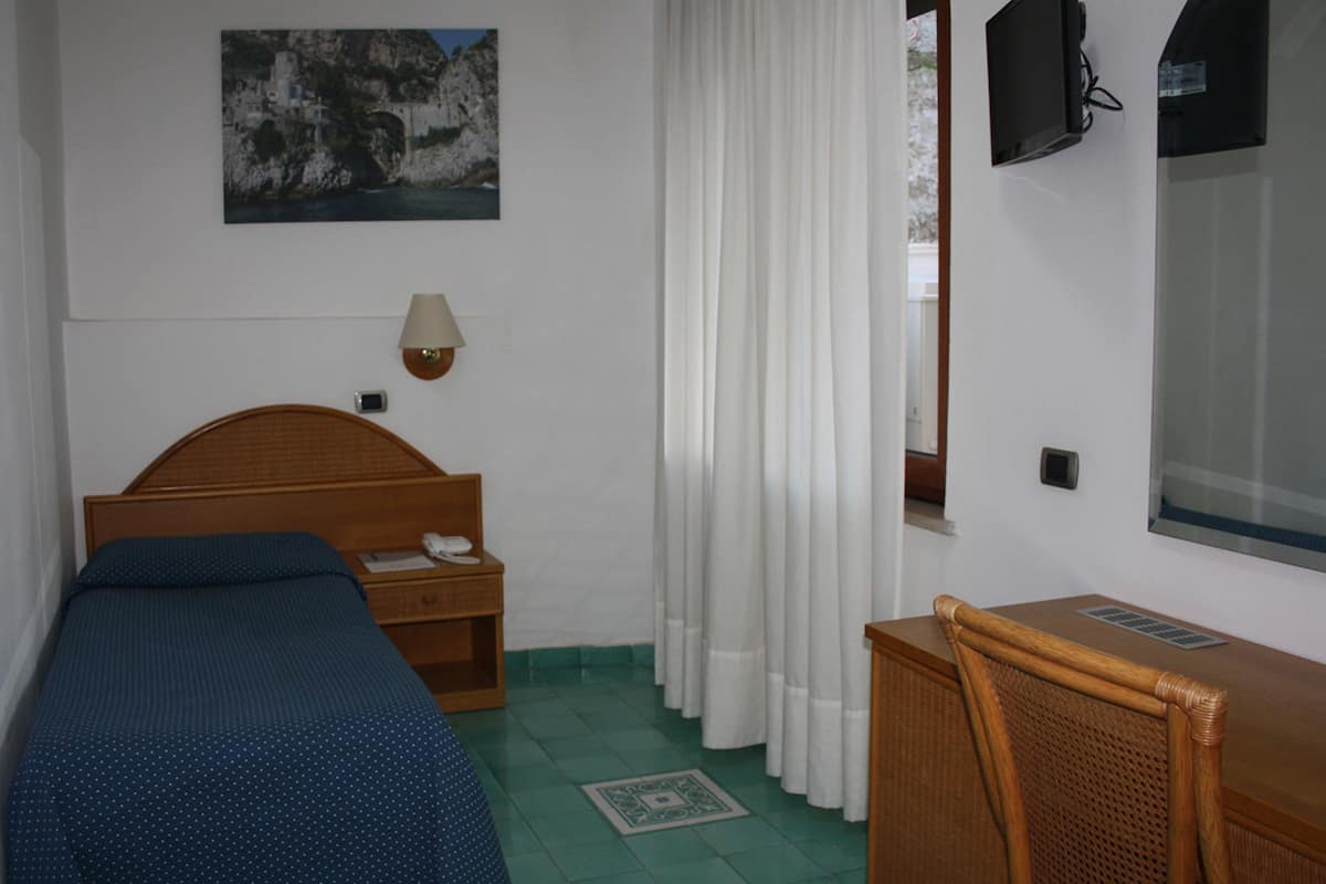Ein Schlafzimmer mit einem hölzernen Bett, einem Schreibtisch, einem Stuhl, einem Fernseher und einem Bild an der Wand.