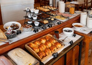A buffet with various food items, including pastries, bread, and condiments.