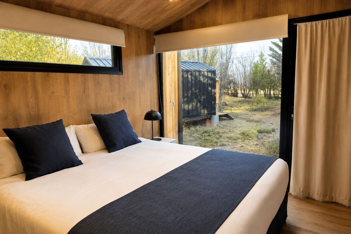 Un dormitorio con una cama grande, paredes de madera, una ventana y vistas al exterior.