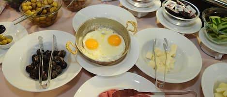 A buffet with various food items including eggs, cheese, ham, and olives.