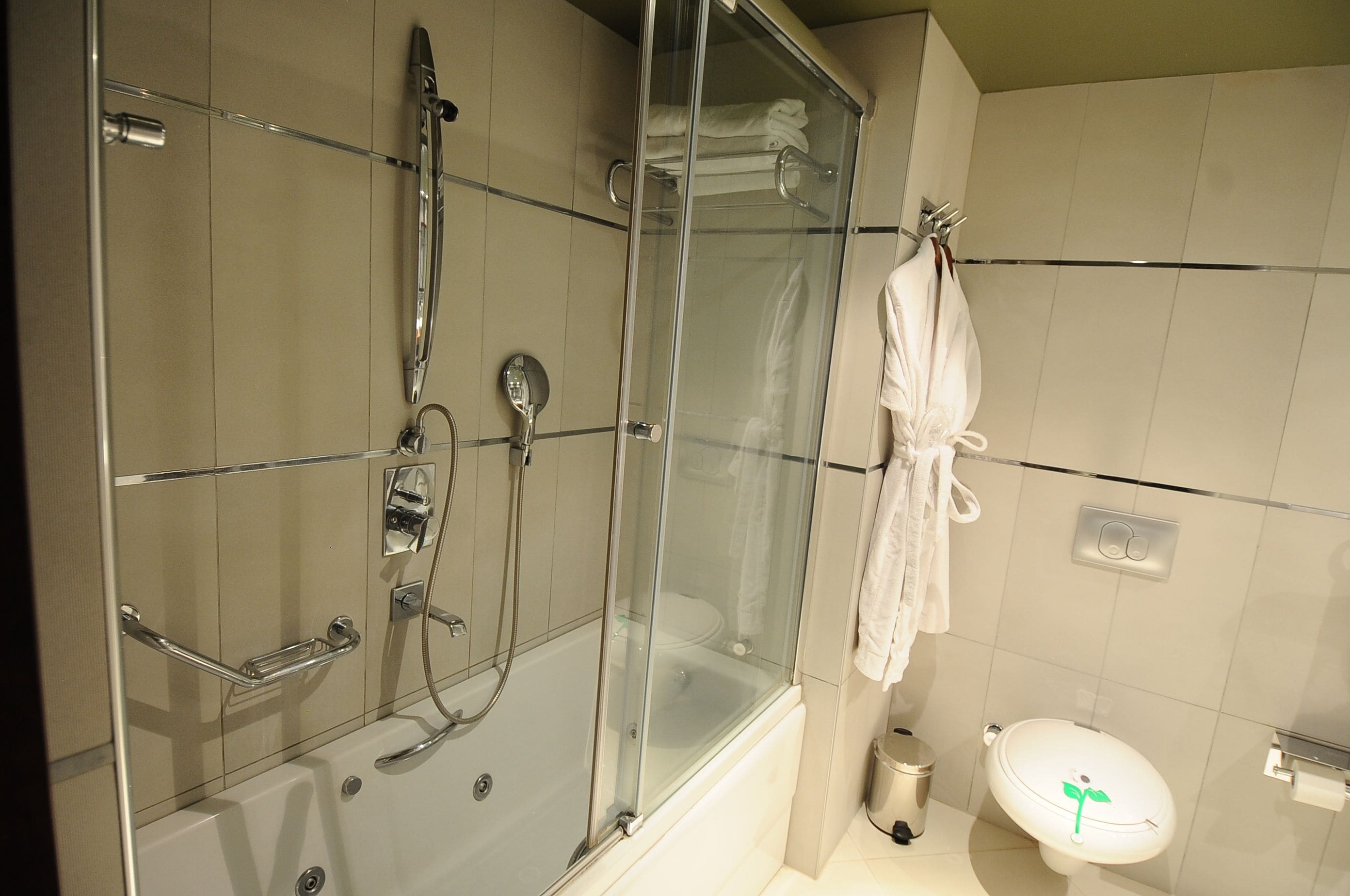 A modern bathroom with a glass-enclosed shower, a bathtub, a toilet, and a towel rack.