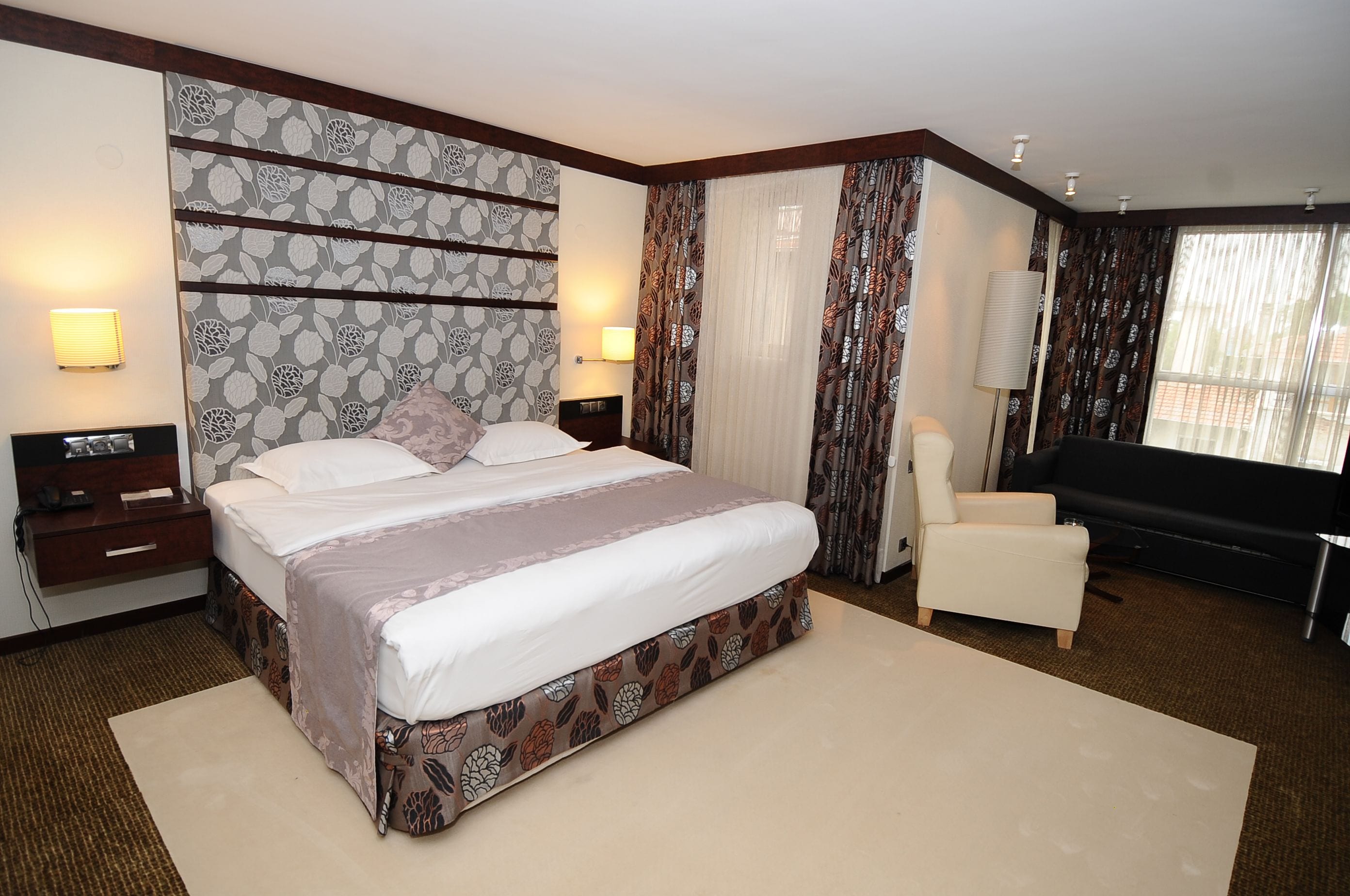 Ein Hotelzimmer mit einem großen Bett, einem Schreibtisch, einem Sessel und einem Fernseher.