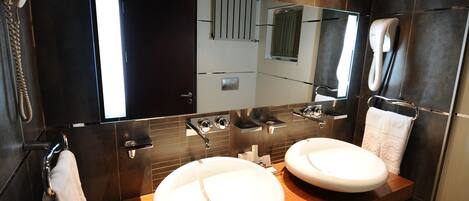 A modern bathroom with two sinks, a large mirror, and a towel rack.