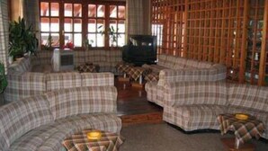 Una sala de estar con un conjunto de sofá, una televisión y un separador de madera.