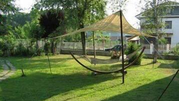 A hammock suspended between two poles in a grassy yard with a house in the background.