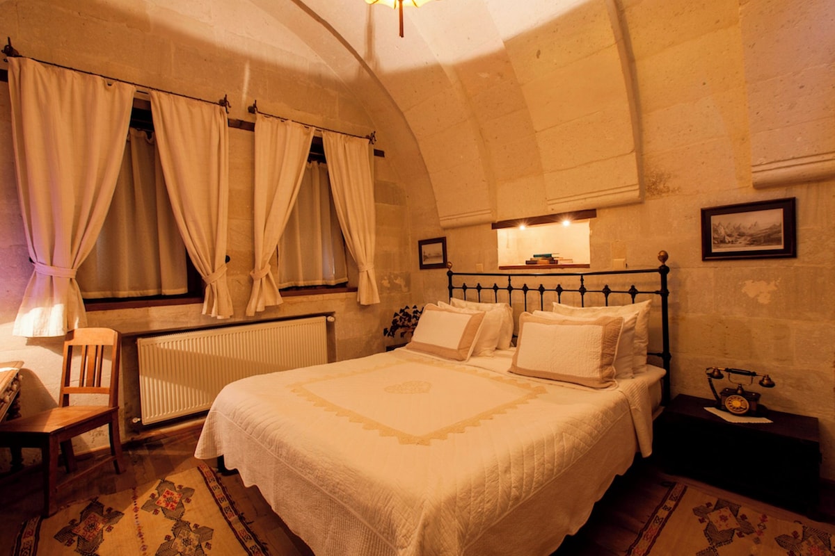 Une chambre à coucher avec un grand lit, une chaise, un radiateur et une table de chevet avec une lampe.