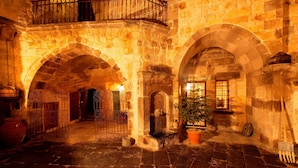 An interior courtyard with stone arches, a small tree, and a metal gate. - Kale Konak (Nevsehir)