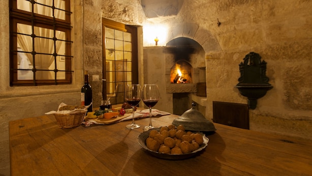 A rustic interior with a stone fireplace, wooden table, and a basket of nuts. - Kale Konak (Nevsehir)