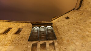 A stone building with a large arched window and a smaller window to the left. - Kale Konak (Nevsehir)