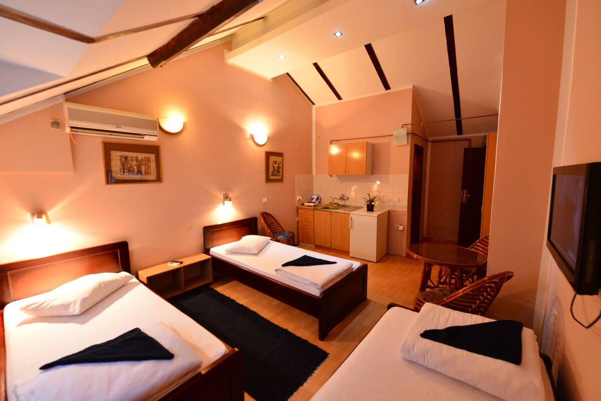 A hotel room with two beds, a kitchenette, and a dining area.