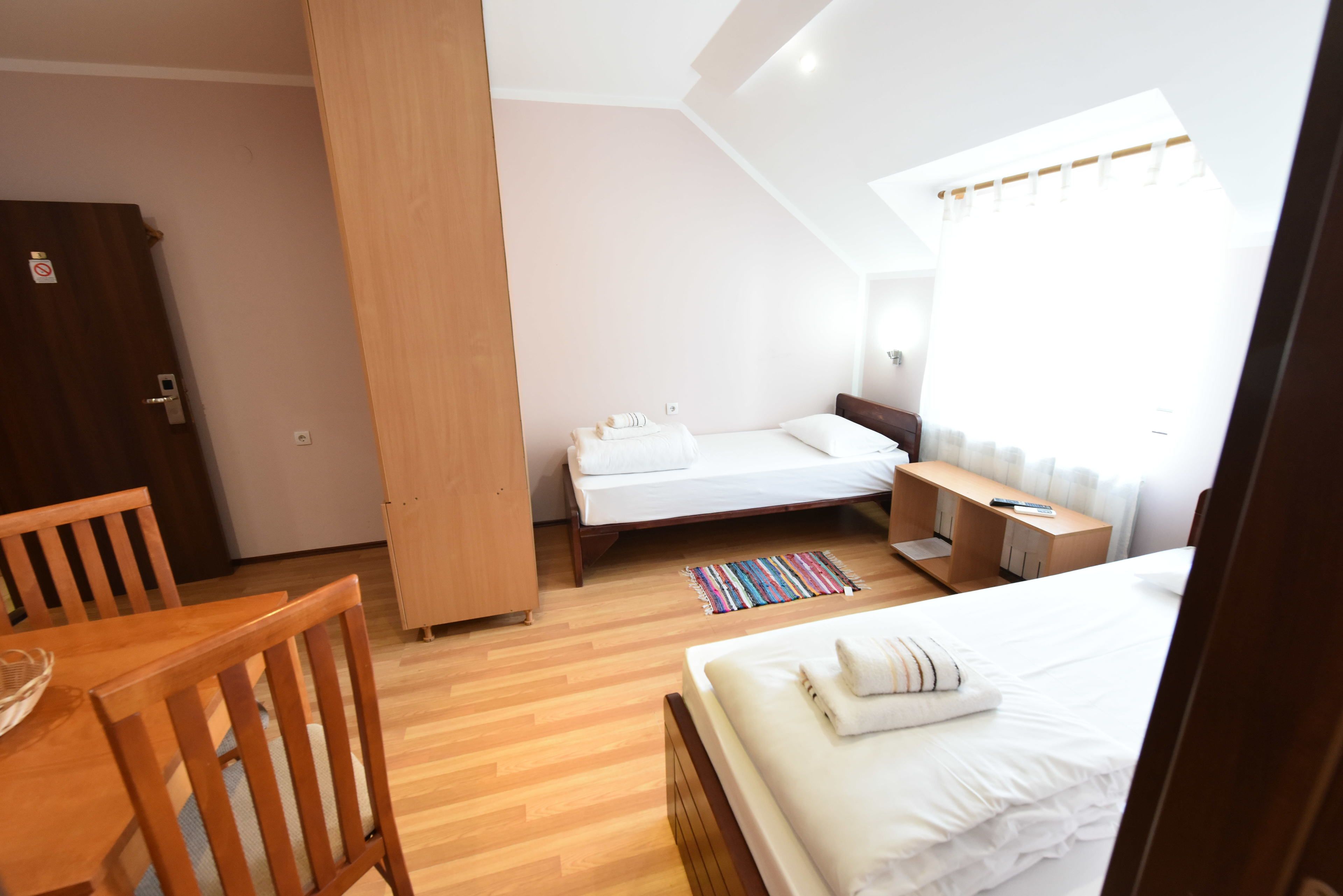 A bedroom with a bed, a desk, a chair, and a wooden wardrobe.