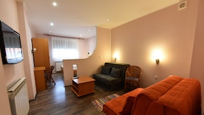 A modern living room with a sofa, a small table, and a television mounted on the wall. - Prenociste Stojic Novi Sad (Novi Sad)