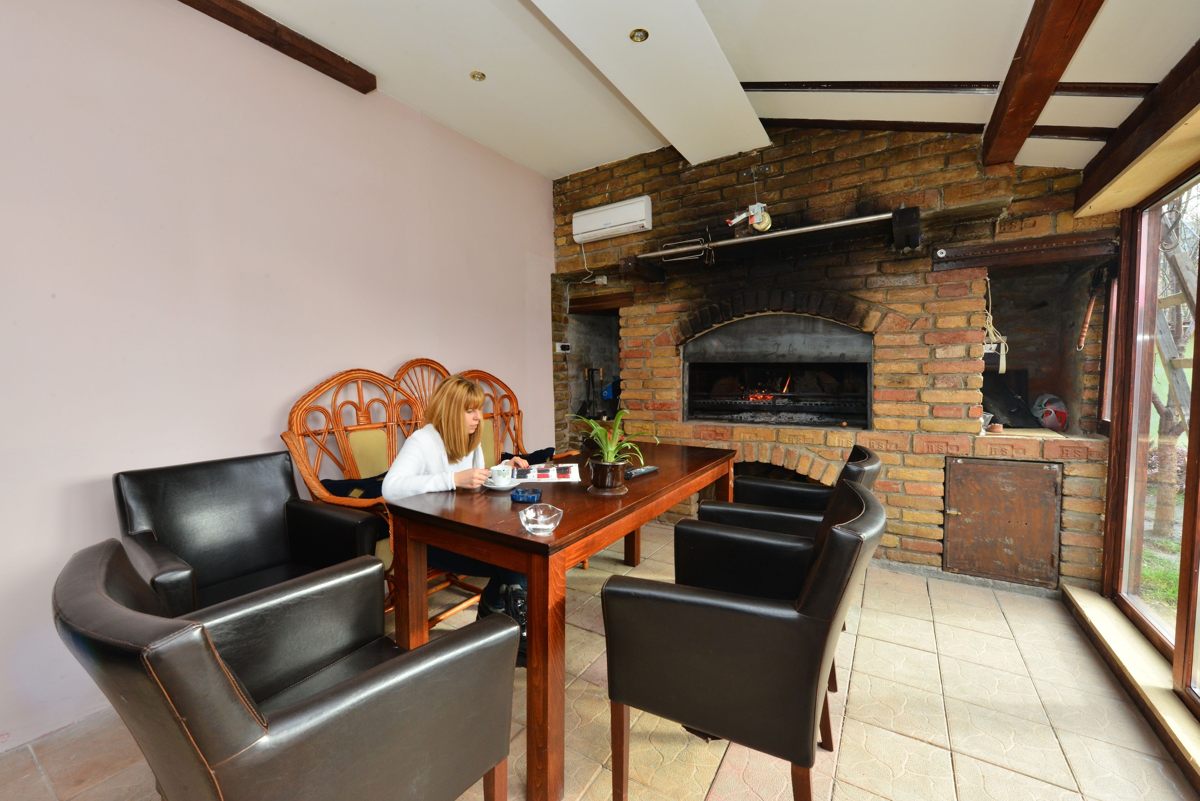 A dining area with a brick fireplace, wooden table, and leather chairs.