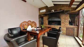 A dining area with a brick fireplace, wooden table, and leather chairs.